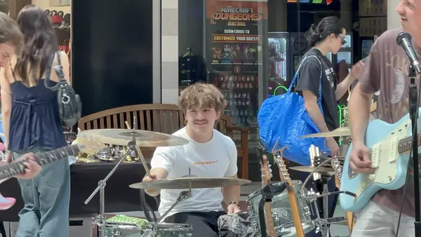 DogPaw drummer smiling mid-song at the Provo Farmers Market